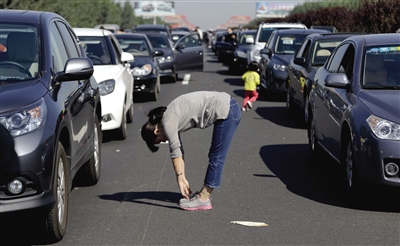 昨日，京沪高速天津段上，一名小男孩在车顶上遥望堵车长龙，甚至有车主在高速路上踢毽子、做体操消磨时间。廖攀 摄