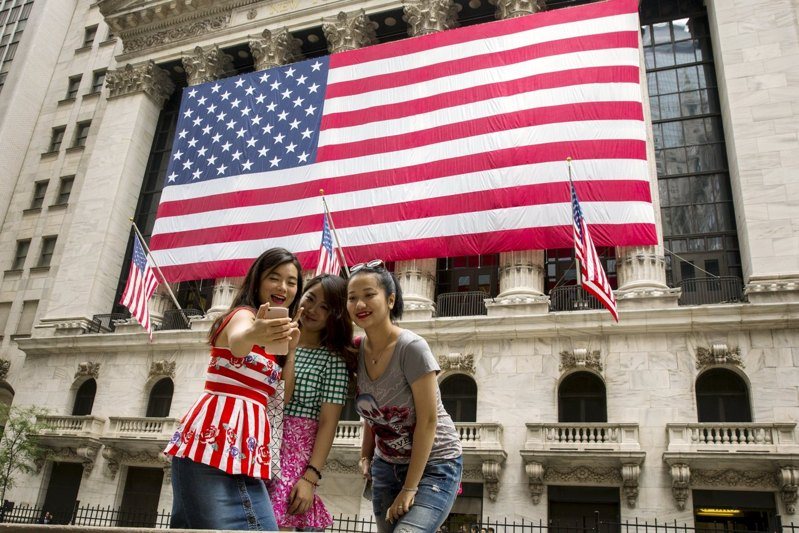 中國外交部和駐美大使館稱赴美人員遭到美方無端盤查,呼籲赴美的中國旅客提高警覺。圖為中國遊客在紐約證券交易所前自拍。(路透)